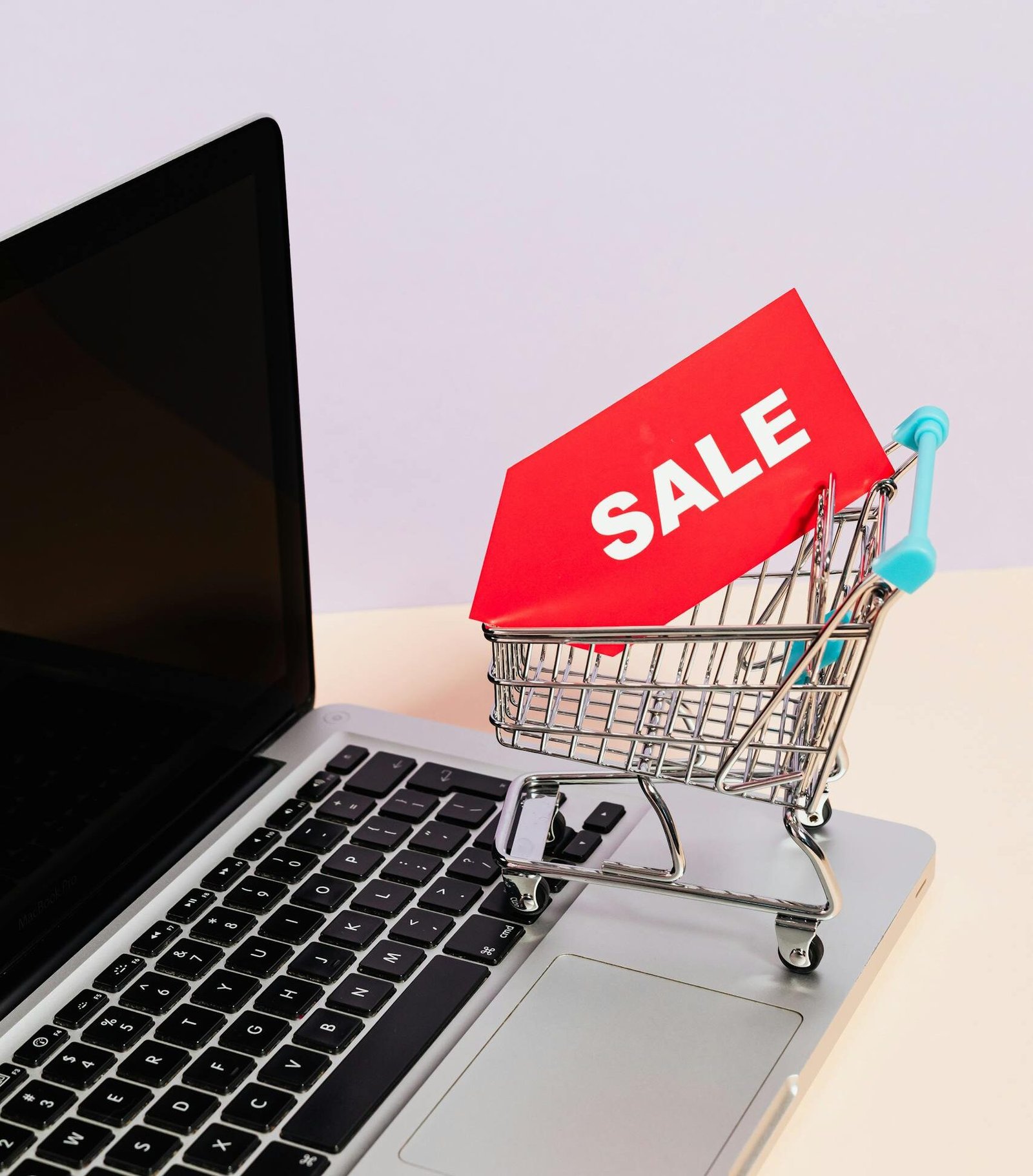 Mini shopping cart with sale tag on laptop for online shopping theme.